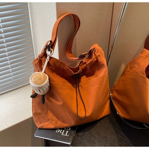 Close-up of orange nylon tote bag with drawstring closure and cute coffee cup plush charm
