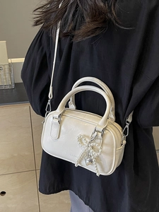 Creamy white oil wax leather pillow bag with beaded bow charm and silver heart detail