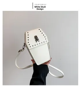 Detail of coffin-shaped white crossbody bag featuring skull metal ornament and rivet studs
