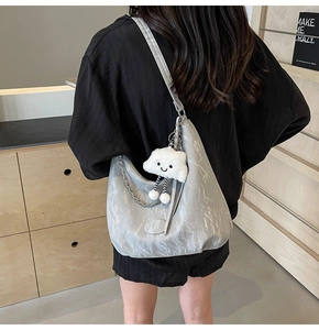 Detail of silver pleated hobo bag with metal chain and cute white cloud pendant
