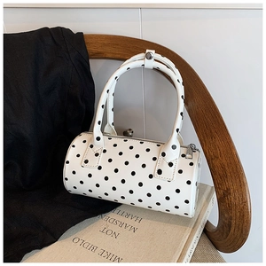Close-up of white cylindrical Boston bag with black polka dots and silver metal zipper