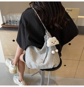 Detail view of large silver-grey hobo bag with metal chain and cute white cloud charm