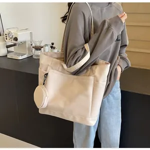 Frau trägt beige Nylon-Tragetasche mit kleinem Münzfach in einer Café-Umgebung