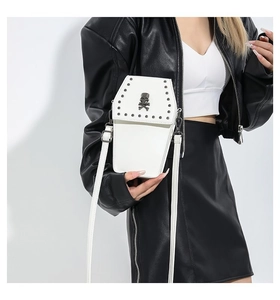 Detail of white coffin shaped crossbody bag with skull logo and silver rivet accents