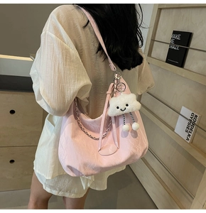 Detail of pink hobo shoulder bag with textured fabric, silver chain and plush charm