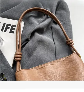 Close-up of brown pebbled leather bucket bag with a stylish knotted handle design