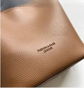 Close-up of brown lychee grain leather bucket bag with FASHION & BAGS embossed logo