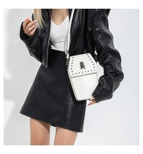 Detail of white coffin cross-body bag with silver studs and metal skull on leather