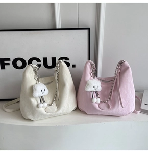 Detail of soft textured shoulder bag with metal chain strap and cloud plush pendant