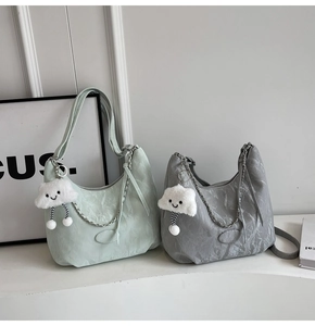 Detail view of mint green and dark grey pleated shoulder bags with silver chains