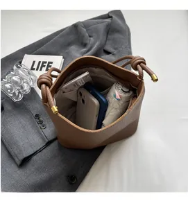 Brown bucket bag detail showing interior capacity for phone and umbrella with gold hardware