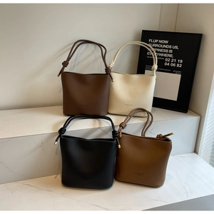 Detail view of four textured leather bucket bags in various colors with knotted straps