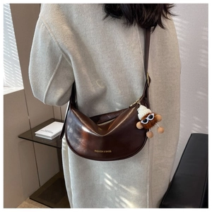 Dettaglio borsa hobo in pelle marrone con logo dorato e simpatico ciondolo in peluche