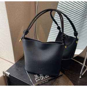 Detail of black lychee grain leather bucket bag featuring a unique knotted handle design