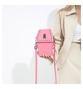 Detail of pink gothic coffin crossbody bag with metal skull emblem and rivet studs