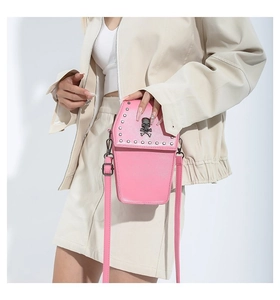 Detail view of pink coffin-shaped crossbody bag with silver studs and skull emblem