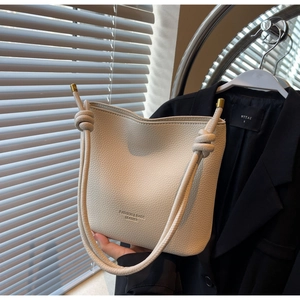 Detail view of cream bucket bag in lychee pattern leather with a unique knotted handle