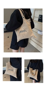 Detail view of large beige tote bag featuring silver eyelets and gothic punk studs