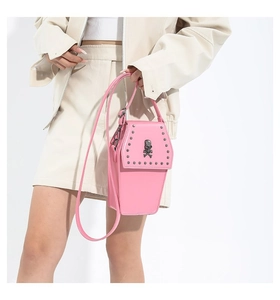 Detail view of pink coffin-shaped crossbody bag with metal skull and silver studs