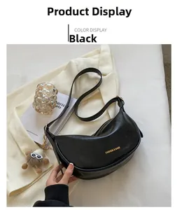 Dettaglio di una borsa a spalla nera a mezzaluna con scritte dorate e ciondolo