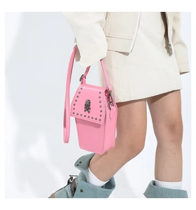 Pink coffin-shaped crossbody bag with silver skull detail shown on walking model