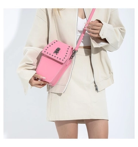 Detailed view of pink crossbody phone bag with black rivets and skull logo on model