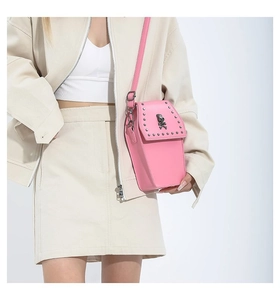 Detail of pink coffin-shaped crossbody bag with silver studs and gothic skull ornament