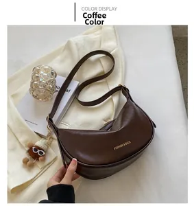 Dettaglio della borsa a tracolla a mezzaluna color caffè con scritta dorata e ciondolo morbido