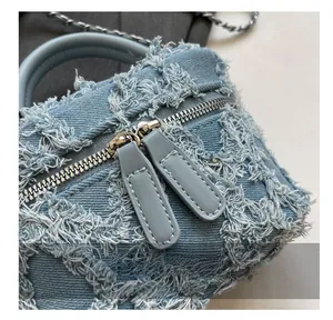 Close-up of smooth dual-zipper and distressed denim texture on the crossbody bag