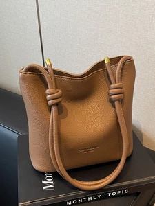 Brown litchi grain leather bucket bag with knotted straps and gold metal accents