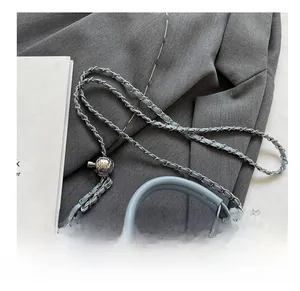 Detail of blue denim crossbody bag featuring frayed edges and adjustable gold ball chain
