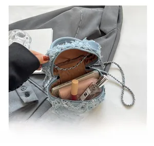 Internal view of a denim mini box bag showing the main compartment and silver chain