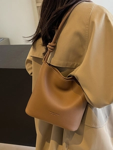 Minimalist brown pebbled leather bucket bag with knotted shoulder strap for women