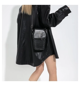 Detail showing matte leather coffin-shaped bag with metal cross and silver studs