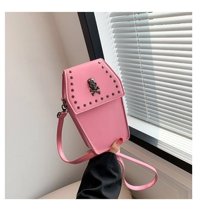 Detail view of pink coffin-shaped crossbody bag with metal rivets and silver skull emblem