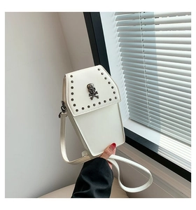 Detailed view of white coffin-shaped crossbody bag with silver studs and skull emblem