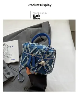 Detail of dark blue denim crossbody bag with frayed diamond quilting and silver ball chain