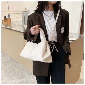 Detail view of white leather handbag with soft texture and stylish side pleats on model
