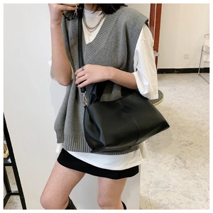 Detail view of the elegant black leather tote bag with slender straps and metal buckles