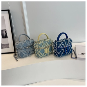 Detailed macro shot of three denim bucket bags with fringe diamond pattern and chains