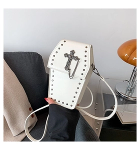Close-up of white coffin-shaped crossbody bag featuring metal cross and silver rivets