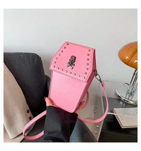 Detail view of pink coffin crossbody bag with a skull emblem and silver metal studs