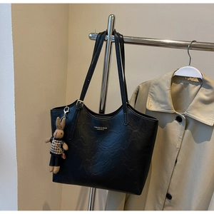 Detail of a black tote bag with natural texture, featuring a cute rabbit charm and logo