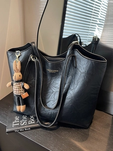 Classic black leather tote bag with a cute rabbit charm in a modern minimalist setting