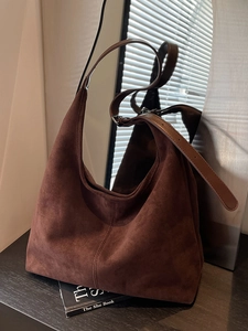 Sac seau en daim marron avec bandoulière en cuir sous un éclairage intérieur élégant