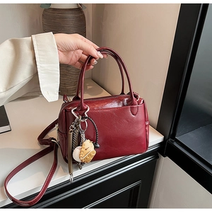 Détails d'un sac à main vintage rouge foncé avec des charms de baseball créatifs