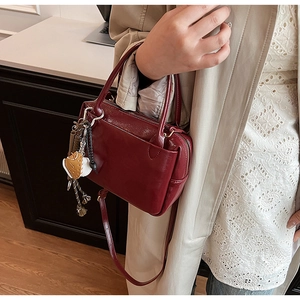 Détail du sac à main bordeaux en cuir verni avec poignées et pendentif en forme de cœur