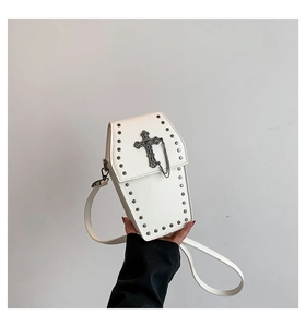Detail of white coffin shaped crossbody bag with gothic rivets and metal cross accessory