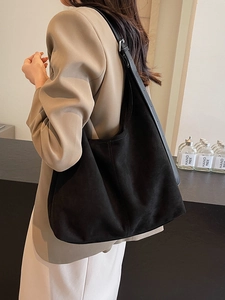Sac seau Hobo vintage en daim noir avec bandoulière réglable porté par un mannequin