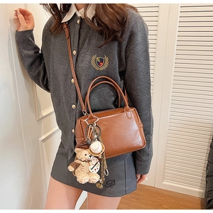 Détail d'un sac à main en cuir marron avec pendentif ours et bandoulière amovible